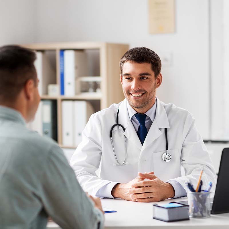 Mediziner erklärt einem Patienten anhand eines Tablets seine Prostatabeschwerden.